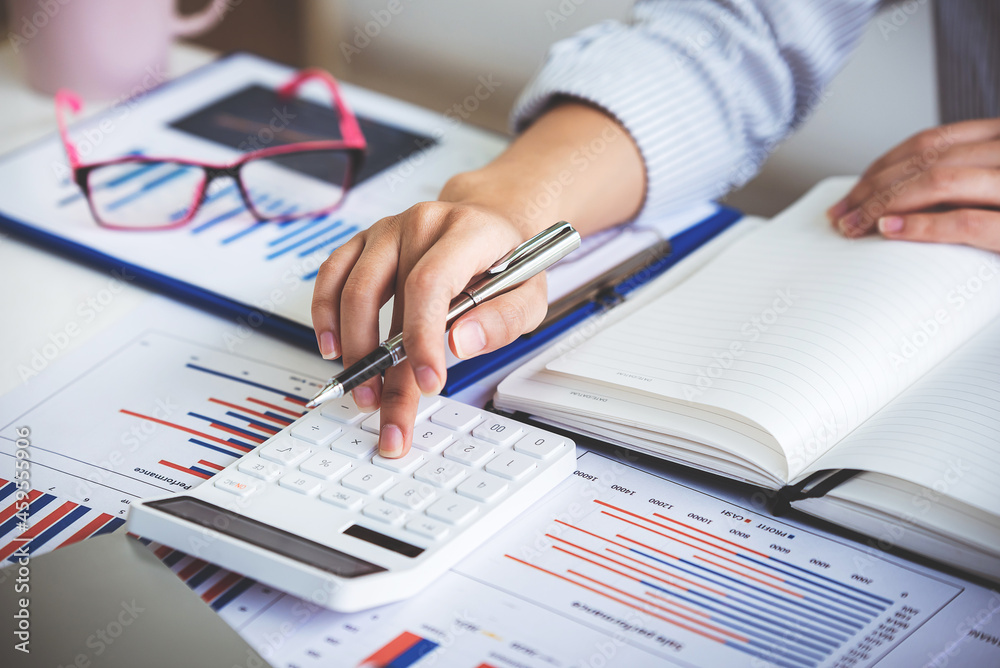 business woman or accountant who are using a calculator to calculate business data Accounting documents and laptop computer at the office business idea