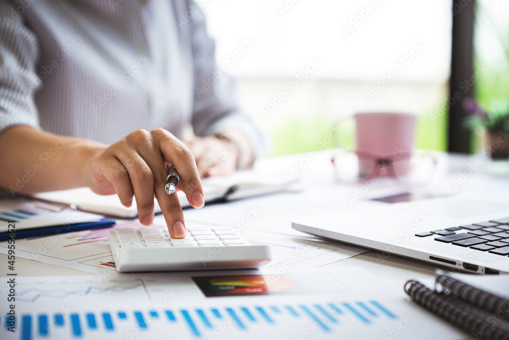 Fototapeta premium business woman or accountant who are using a calculator to calculate business data Accounting documents and laptop computer at the office business idea