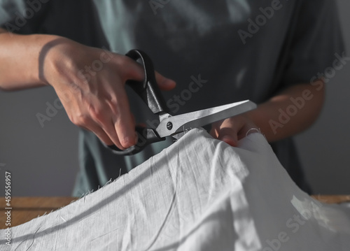 Seamstress hands cutting cloth with sewing scissors. Dressmaker work process close up.