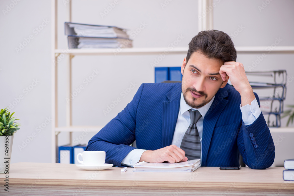 Young handsome employee working in the office
