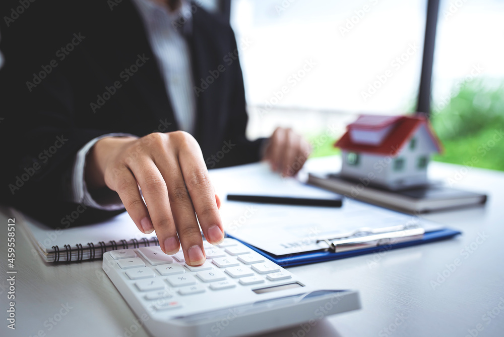 Fototapeta premium A young woman's hand presses a calculator to determine and summarize the cost of mortgage home loans for refinancing plans, lifestyle concepts.