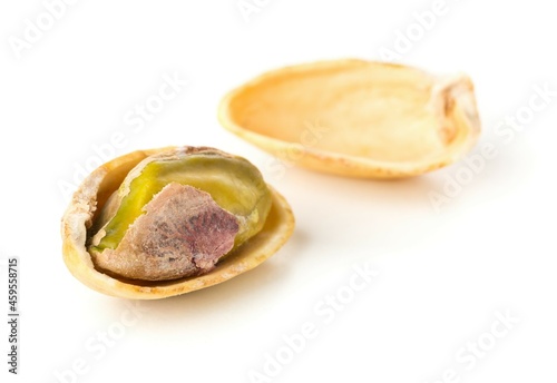 Macro of single salted, roasted green pistachio nut over white background, healthy food snack