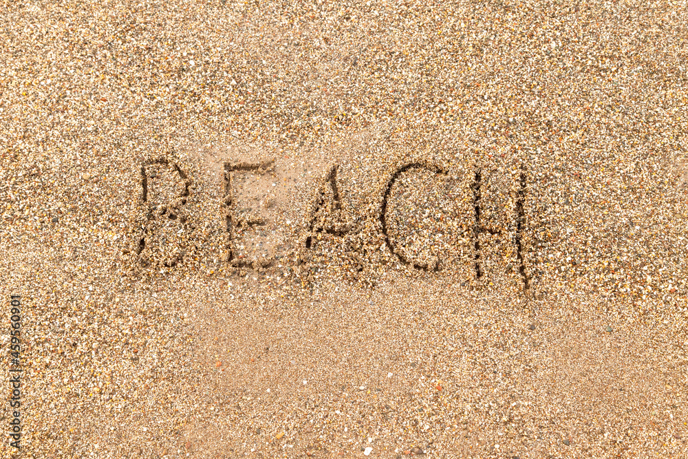 Fototapeta premium The word Beach is written on the sandy seashore