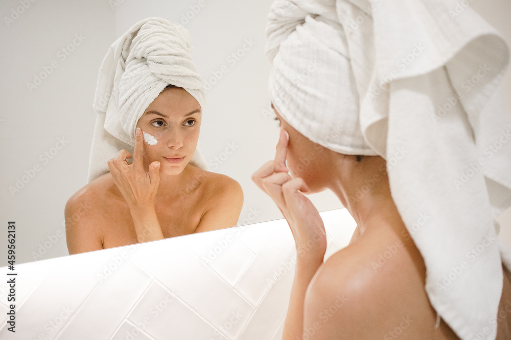 young white woman in the bathroom mirror applying face cream anti acne anti aging spots signs of age confident in the bathroom after shower self care skin care young adult cosmetics plump toned skin young white woman in the bathroom mirror applying face cream anti acne anti aging spots signs of age confident in the bathroom after shower self care skin care young adult cosmetics plump toned skin