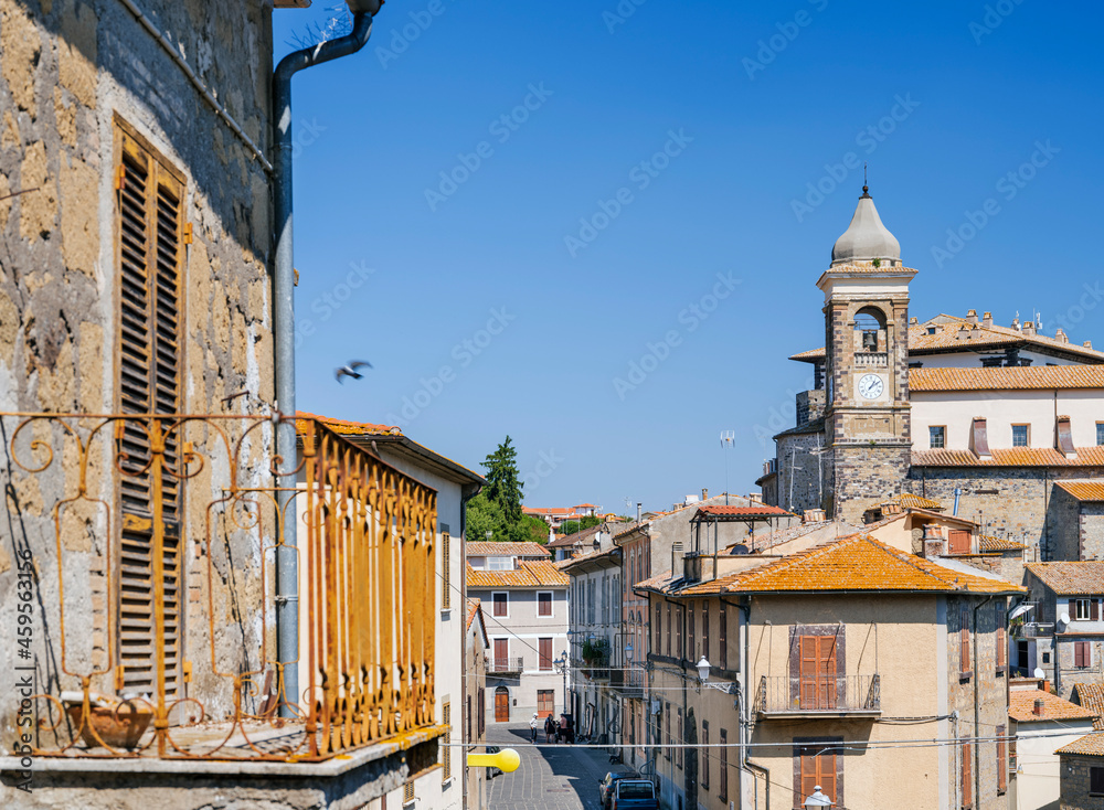 view to clocks tower and old rusty balcony in summer day in italian city Gradoli
