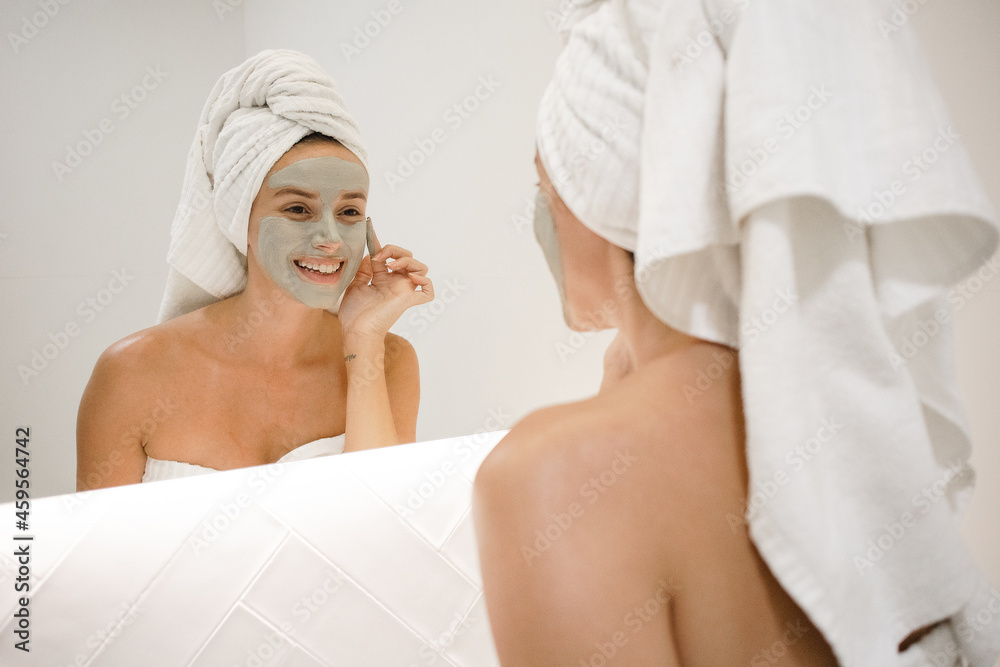 young white woman applying green clay mask bathroom mirror anti acne anti aging spots signs of age oily skin treatment after shower self care skin care young adult cosmetics plump toned spotless skin young white woman applying green clay mask bathroom mirror anti acne anti aging spots signs of age oily skin treatment after shower self care skin care young adult cosmetics plump toned spotless skin