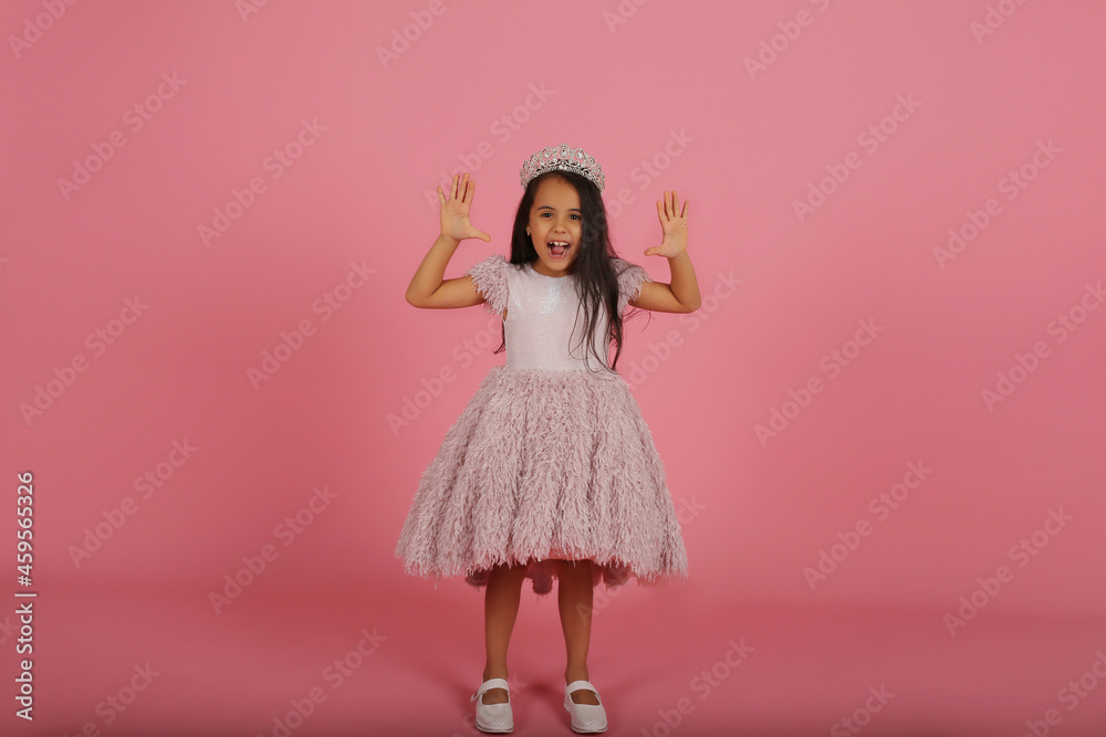 a small dark-skinned beautiful girl in a lush pink dress with a crown on her head a small dark-skinned beautiful girl in a lush pink dress with a crown on her head