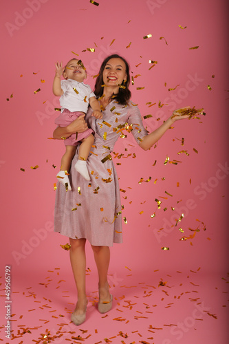 a young mother in a pink dress holds her little son in her arms for a confetti party