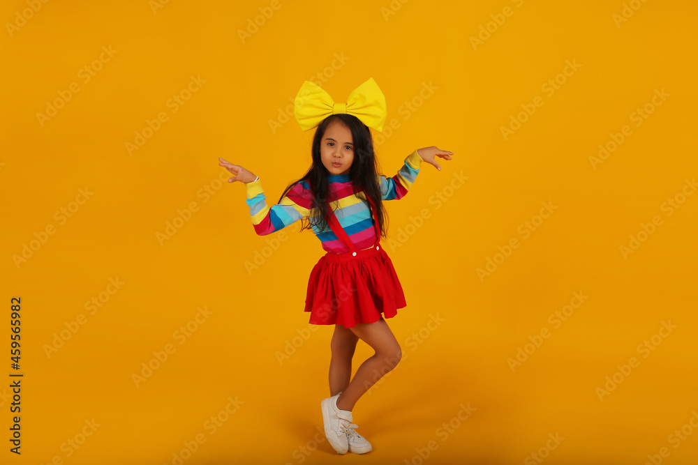 a beautiful happy dark-skinned girl in a red skirt, a colored T-shirt, a yellow bow on her head