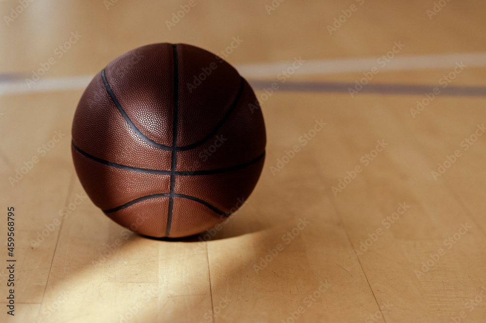 Obraz premium Basketball on hardwood court floor with natural lighting. Workout online concept. Horizontal sport poster, greeting cards, headers, website...