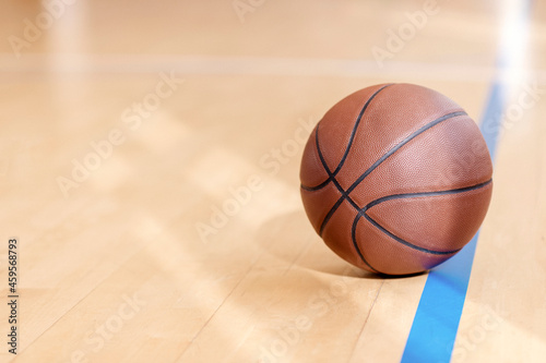 Basketball on hardwood court floor with natural lighting. Workout online concept. Horizontal sport poster, greeting cards, headers, website...