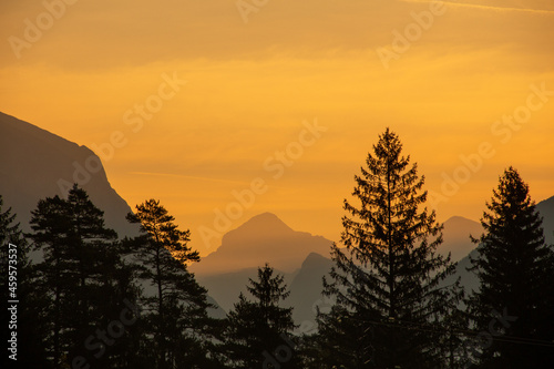 Sunrise in Slovenian Alps silhouette between mountain peaks and trees