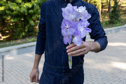 Gardener holds branch of orchids in his hands. Hobbies and gardening. Flower business