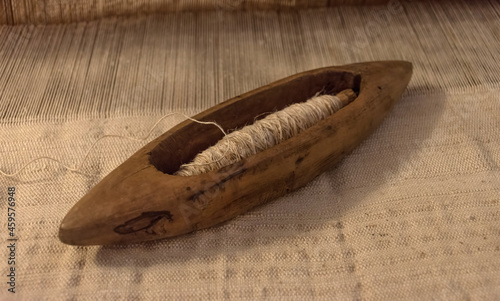 Old wooden spindle for manual spinning, vintage boat shuttle for manual hand weaving. Close up, selective focus photo