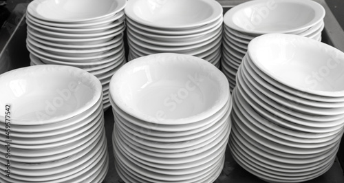 Clean, empty white plates are stacked in piles.