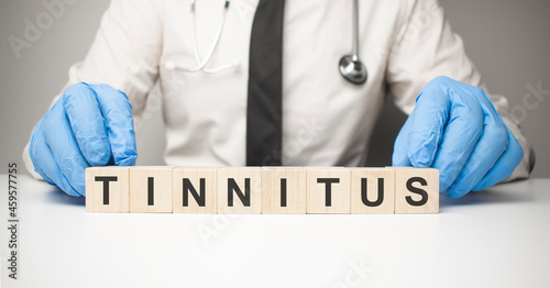 Doctor holds wooden cubes in his hands with text tinnitus photo