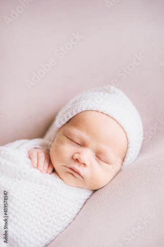 A newborn baby sleeping on a soft pink background. Childhood or parenting concept. Soft focus, copy space.