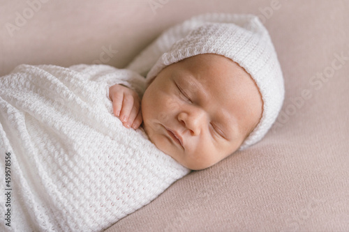 A newborn baby sleeping on a soft beige background. Childhood or parenting concept. Soft focus, copy space.