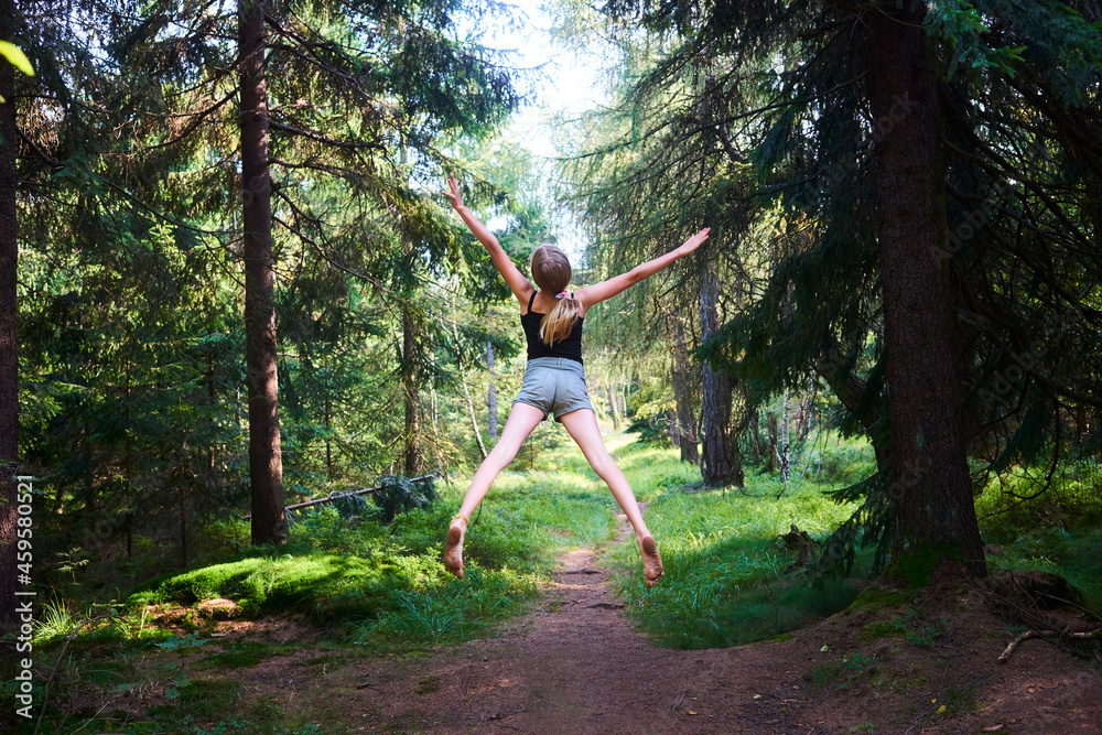 Young girl flying in the air in the woods. Jumping for freedom
