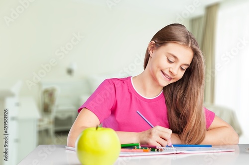 Happy cute schoolgirl drawing picture at home