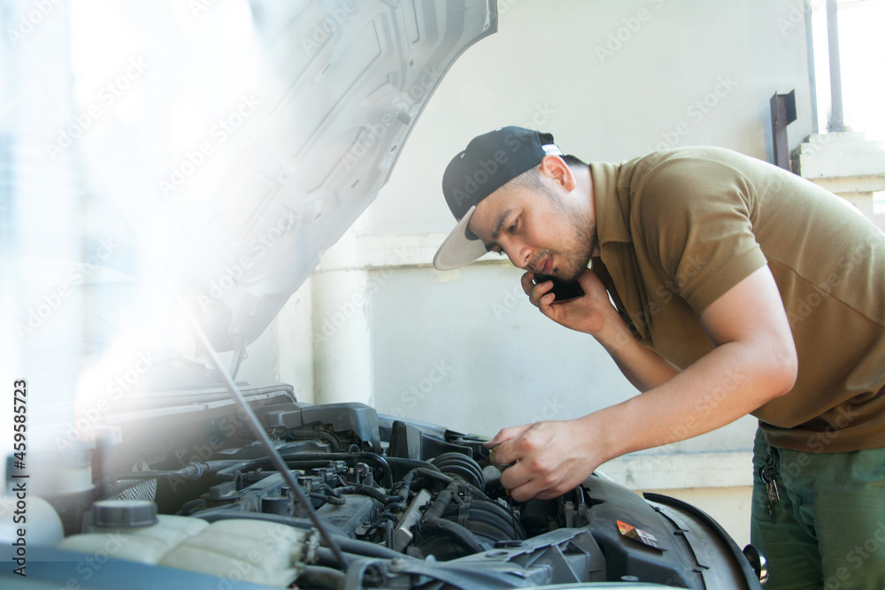 Mechanic checking car and calling customer information Mechanic checking car and calling customer information