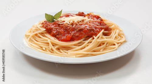 Massa espaguete com molho de bolonhesa e queijo parmesão no prato em fundo branco para recorte photo