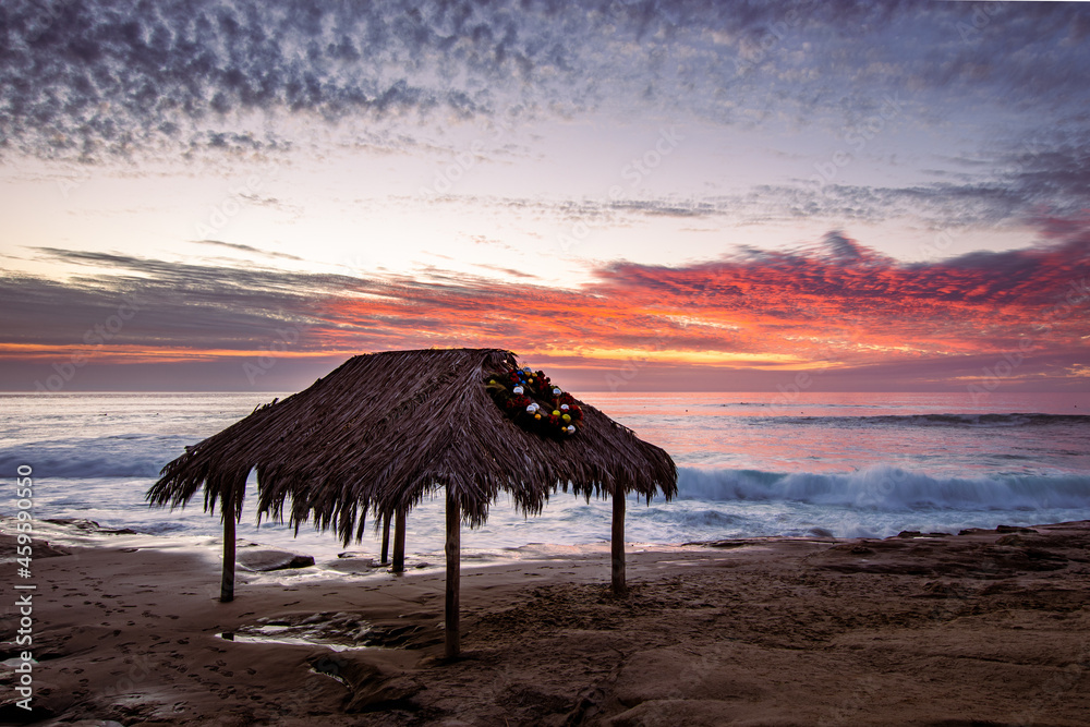 Festive holiday wreath on a thatched roof during a stunning sunset by the Pacific ocean in San Diego California