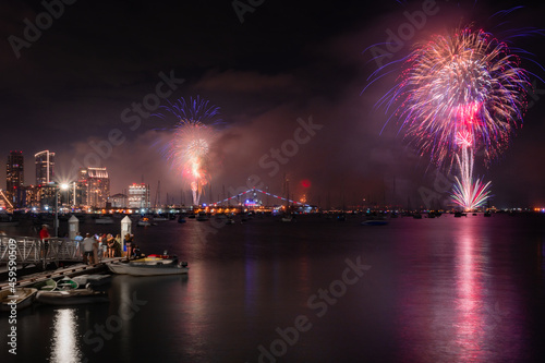 Fourth of July fireworks over the bay in San Diego, California with people watching from the pier