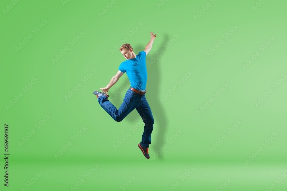 Young cool millennial male jump on the color background