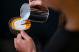 Close up hand of man barista pouring froth milk in espresso coffee in coffee cup making coffee latte art serve to customer. Small business cafe and restaurant owner and part time job working concept
