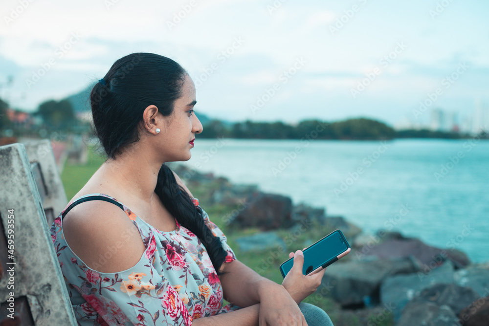 Hispanic girl with cell phone in hand looking out to sea