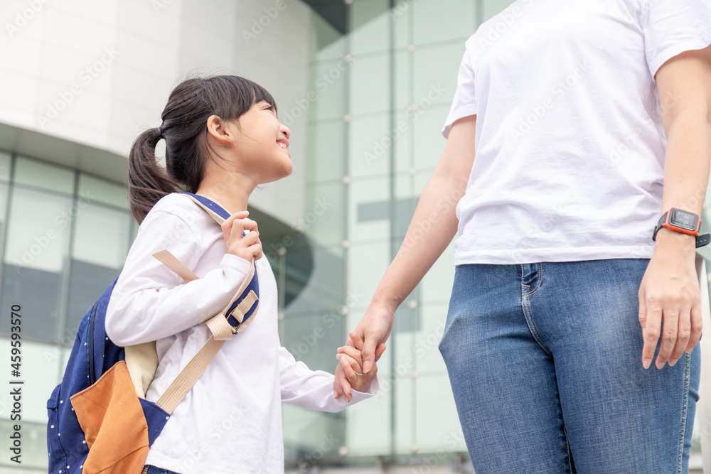 Obraz premium Back to school. Asian mother and daughter pupil girl with backpack holding hand and going to school together. Beginning of lessons. First day