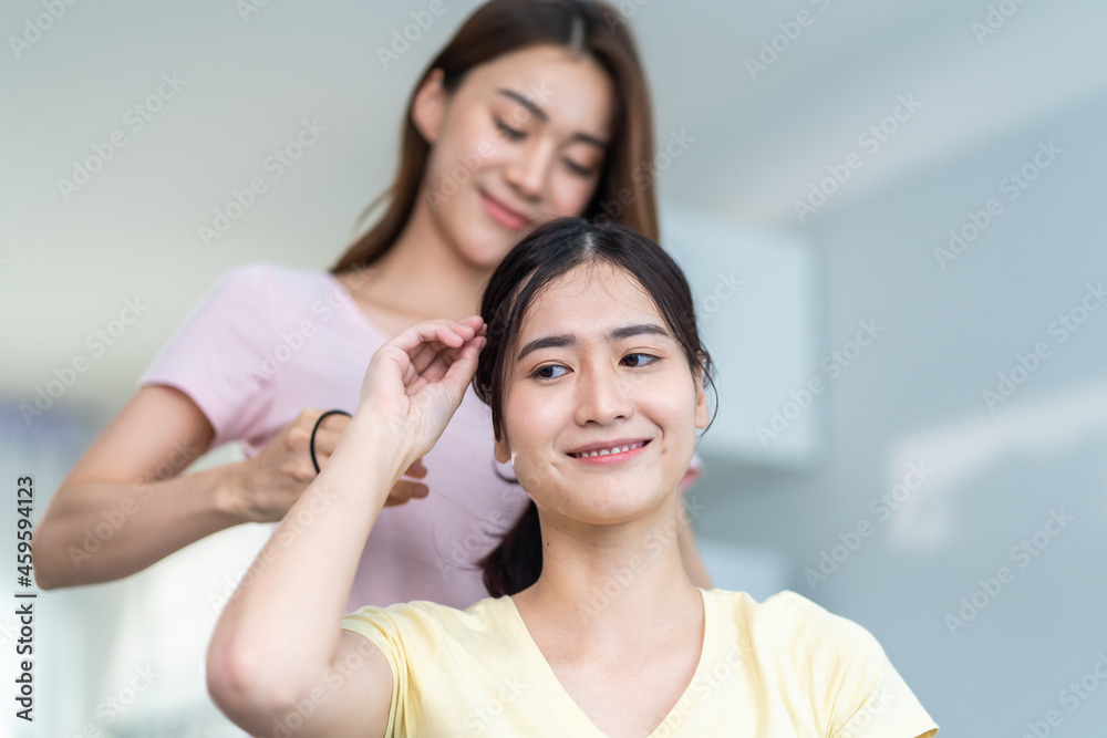 Asian beautiful lesbian women couple combing girlfriends hair in house Asian beautiful lesbian women couple combing girlfriends hair in house