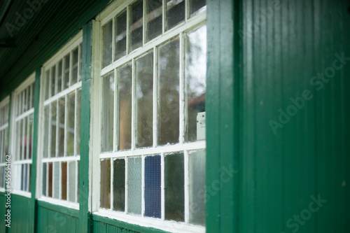 An old window in the village. Colored glass in the window frame. Facade of the house.