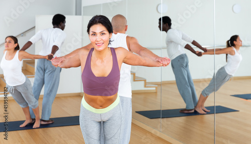 Group of adults doing acroyoga exercises in pairs, exercising partner yoga