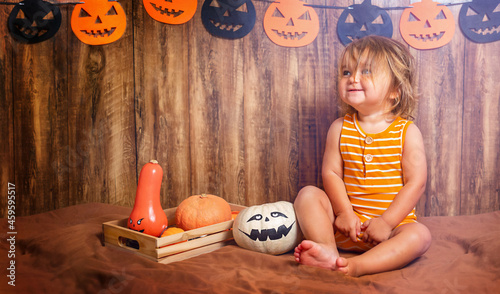 Smiling child sitting with halloween pumpkins photo