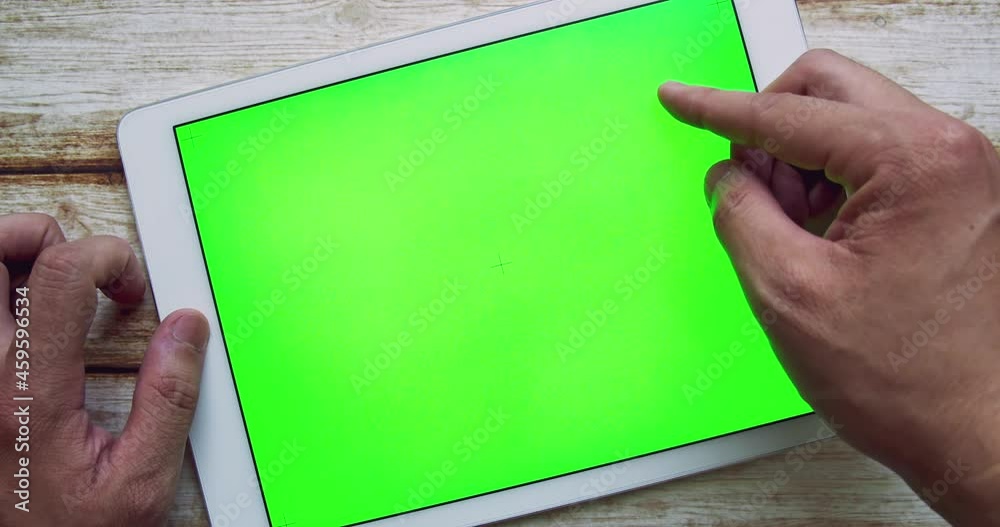 Man using digital tablet with Green Screen chroma key on shabby chick wooden table. Stylish mockup in minimal and cool mood. Dev remote work and e-learning mock up concept. Swipe and Scroll Gesture. Man using digital tablet with Green Screen chroma key on shabby chick wooden table. Stylish mockup in minimal and cool mood. Dev remote work and e-learning mock up concept. Swipe and Scroll Gesture.