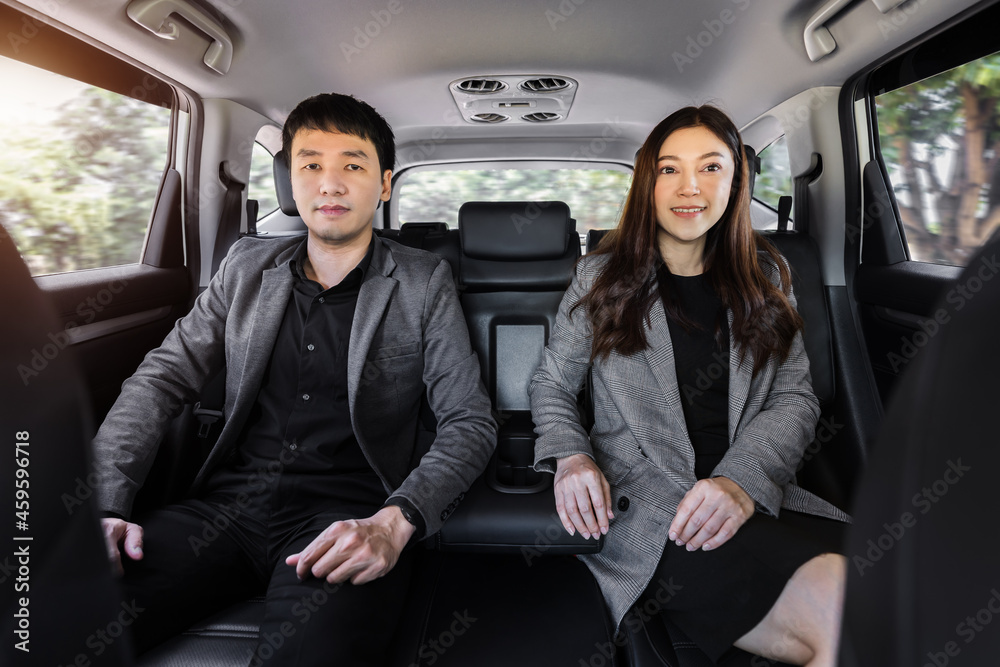 two business man and woman sitting at the back seat of car two business man and woman sitting at the back seat of car