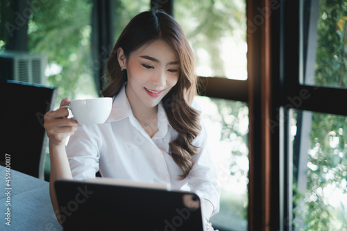 Image of beautiful business woman holds a cup of coffee and checks her email before going to work