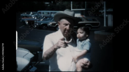 Grandfather Holds Grandson 1974 - A cowboy hat wearing grandfather holds his grandson.  photo