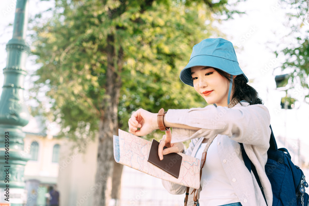 Fototapeta premium Walking young adult southeast asian woman traveller wear blue hat and backpack under sunlight
