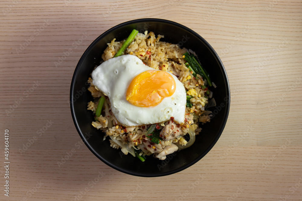 A bowl of fried rice with fried egg on top. A bowl of fried rice with fried egg on top.