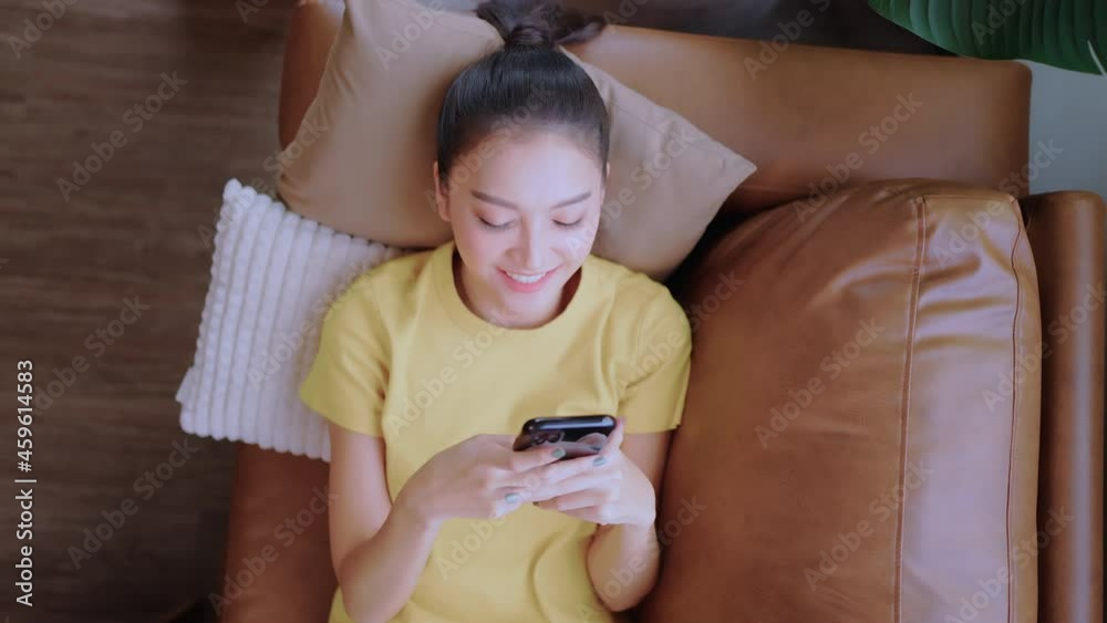 happiness casual asian female woman leisure weekend morning laying down relax on sofa couch hand surf internet on smartphone shopping or social media with smail cheerful smile with pleasure at home