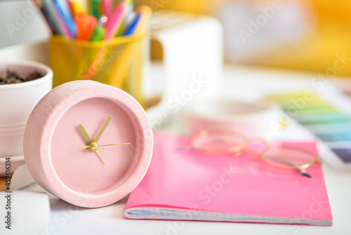Alarm clock and notebook on table in office, closeup