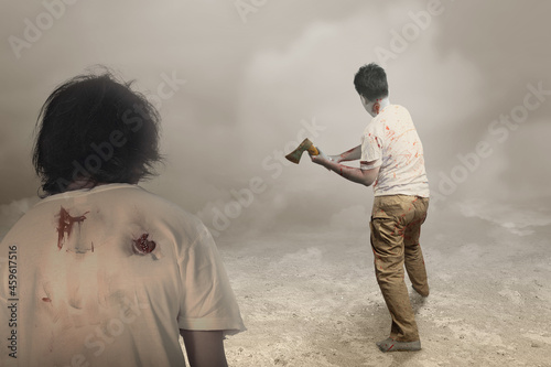 Scary zombie with blood and wound on his body holding ax standing