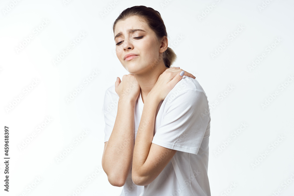 woman in white t-shirt holding shoulders neck pain health problems discomfort woman in white t-shirt holding shoulders neck pain health problems discomfort
