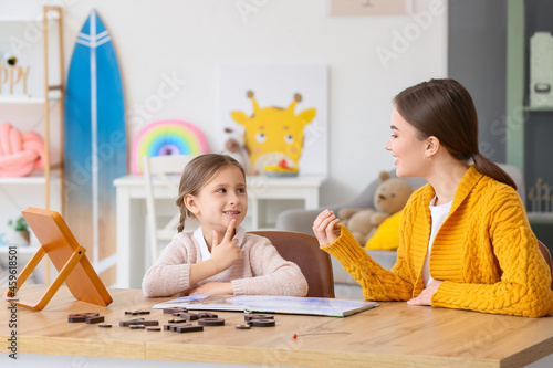 Speech therapist working with cute girl in clinic photo