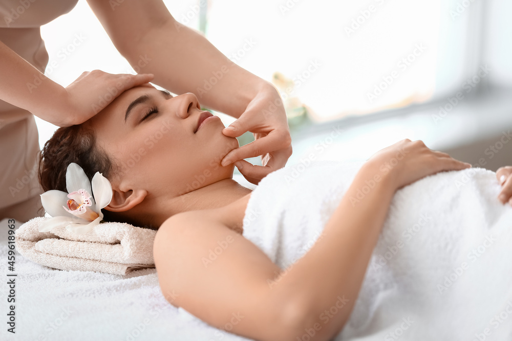 Beautiful young African-American woman getting massage in spa salon Beautiful young African-American woman getting massage in spa salon