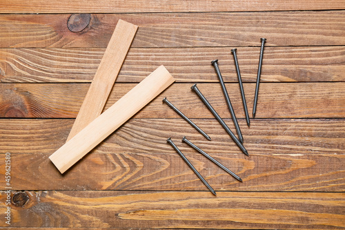 Rulers and nails for furniture assembling on wooden background