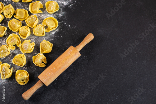 Uncooked tortelloni with mushroom filling on black background,